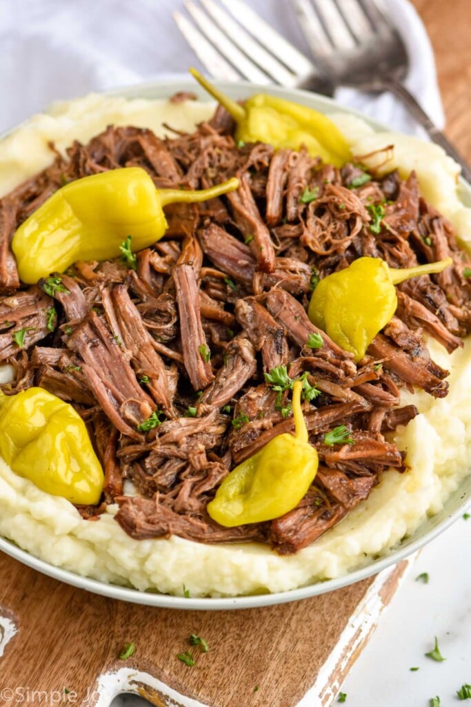 a Mississippi pot roast shredded and over mashed potatoes with fresh pepperoncinis on top