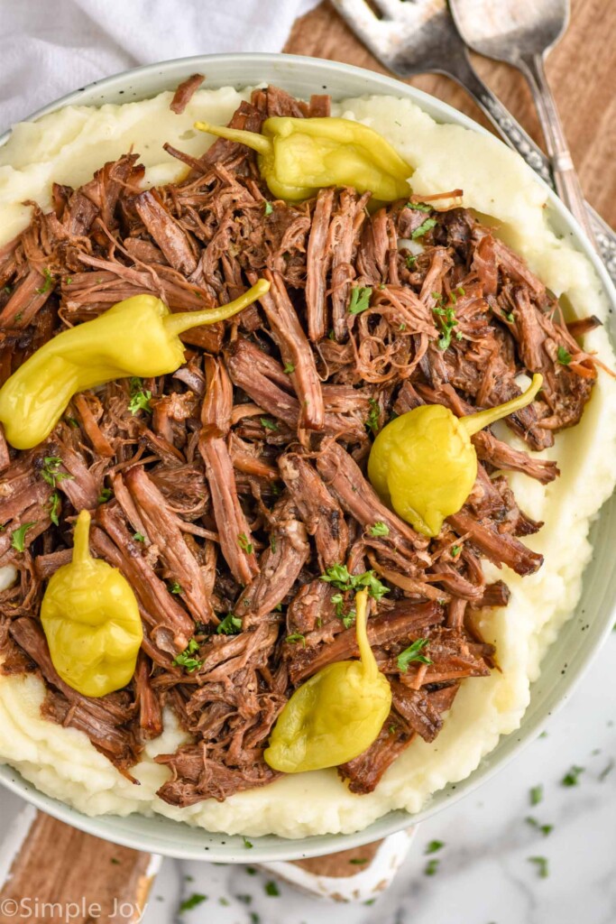 overhead of Mississippi pot roast recipe on a bed of mashed potatoes in a bowl