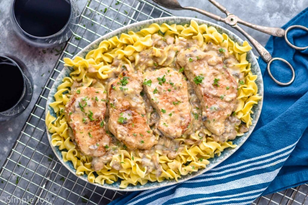 overhead of cream of mushroom pork chops on a bed of egg noodles on a platter