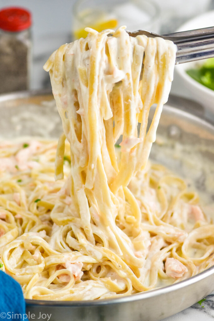 salmon Alfredo recipe being lifted up with some tongs