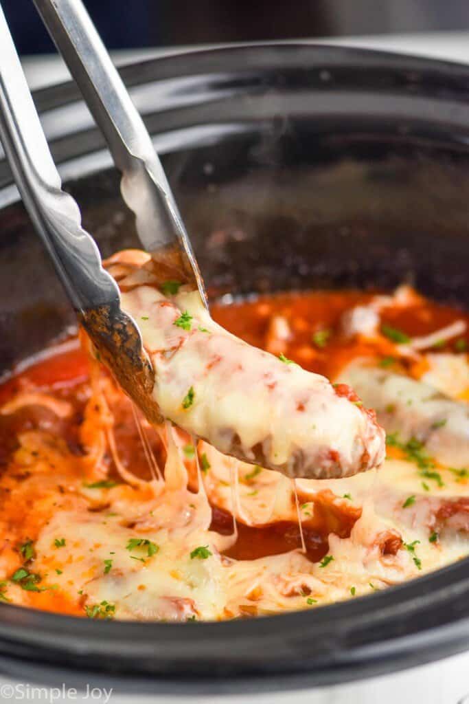 a sausage with melted cheese on it being pulled out of a slow cooker