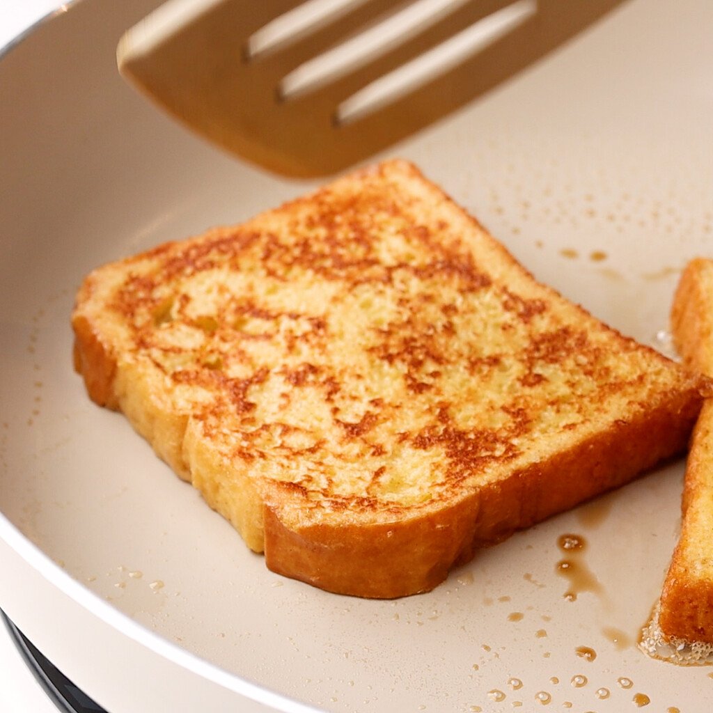 side view of bread being cooked in a skillet to make French toast