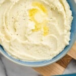 pinterest graphic of overhead of a bowl of mashed cauliflower with butter melting on it