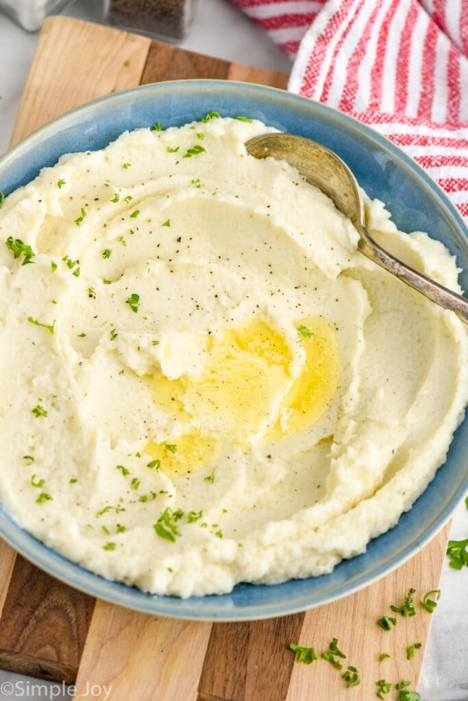 a bowl of cauliflower mashed potatoes with butter, pepper and parsley