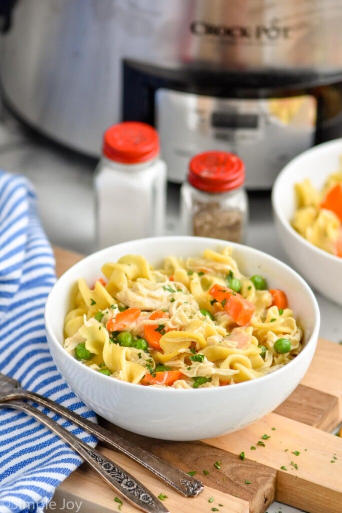 small bowl of chicken and noodles crockpot recipe on a cutting board