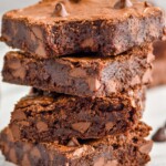 a stack of four chocolate brownies with the top one missing a bite