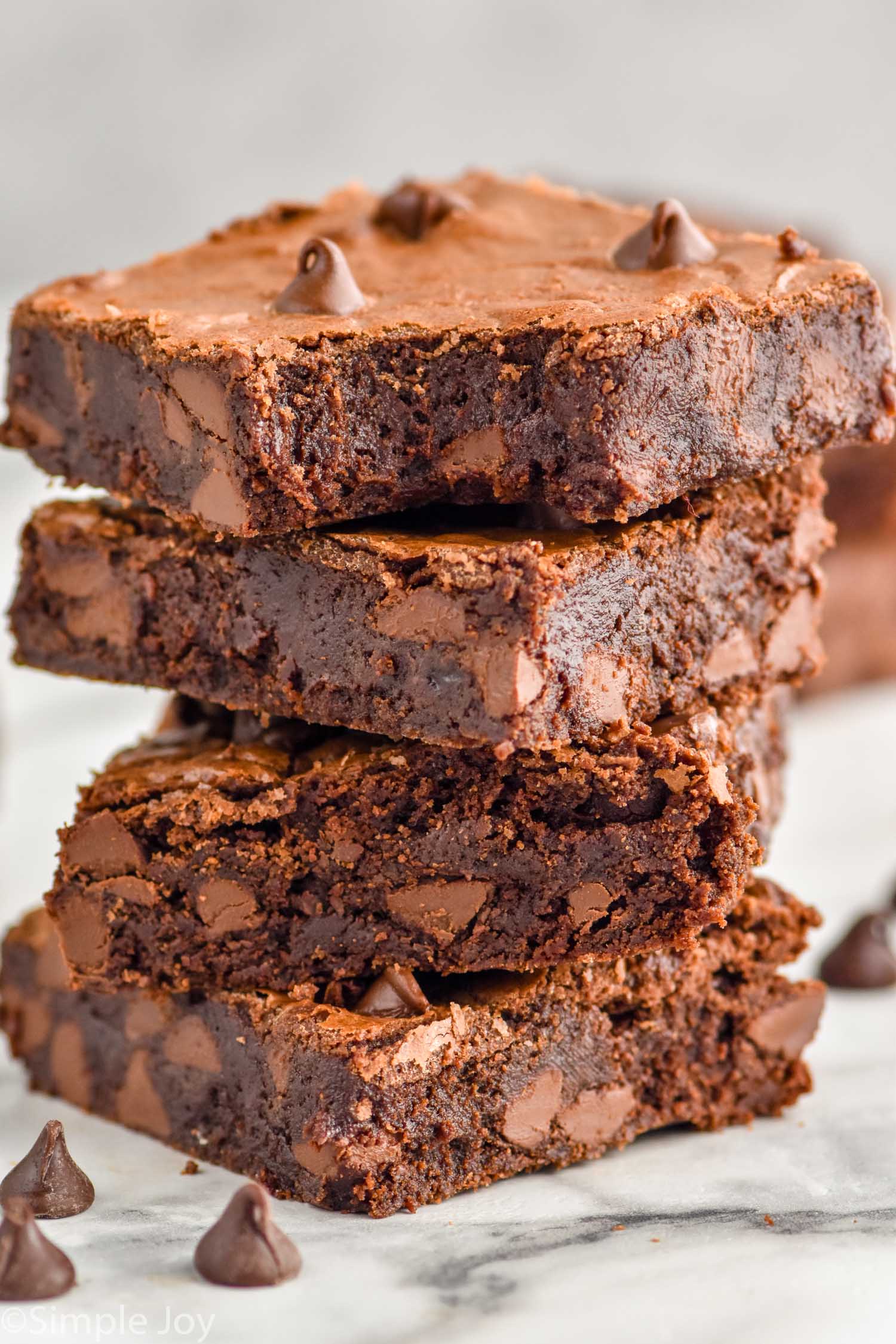 a stack of four chocolate brownies with the top one missing a bite