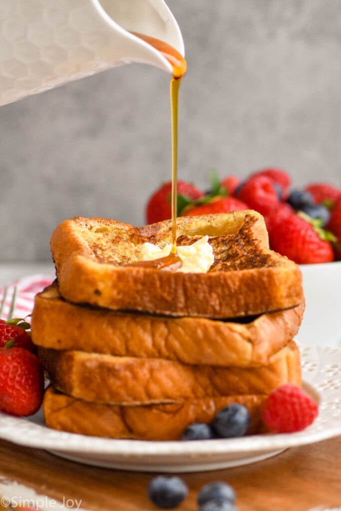 a stack of French toast with syrup being poured on it