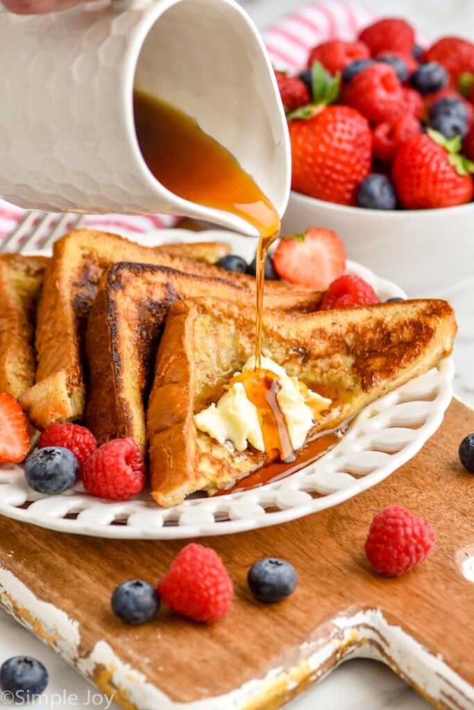 close up of syrup being poured on four pieces of triangle cut French toast