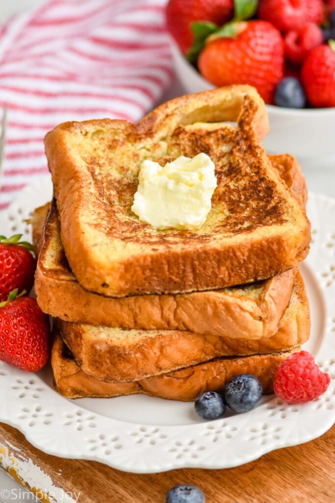 four square pieces of French toast stacked with butter on top