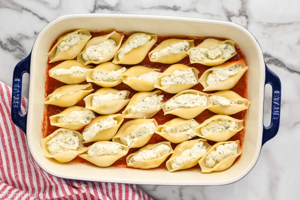 overhead of a casserole dish full of stuffed shells before they are covered with sauce, cheese, and baked
