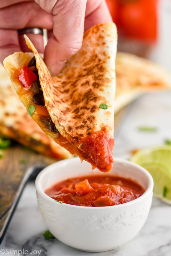 slice of vegetarian quesadilla being dipped in salsa