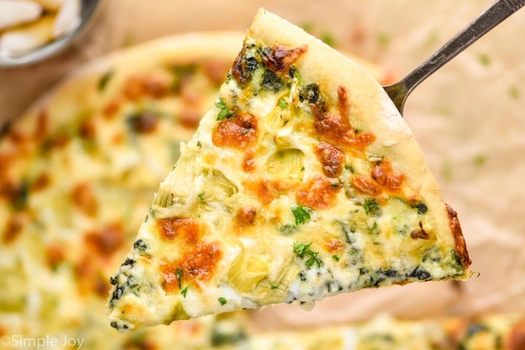 overhead of a piece of spinach pizza on a spatula 