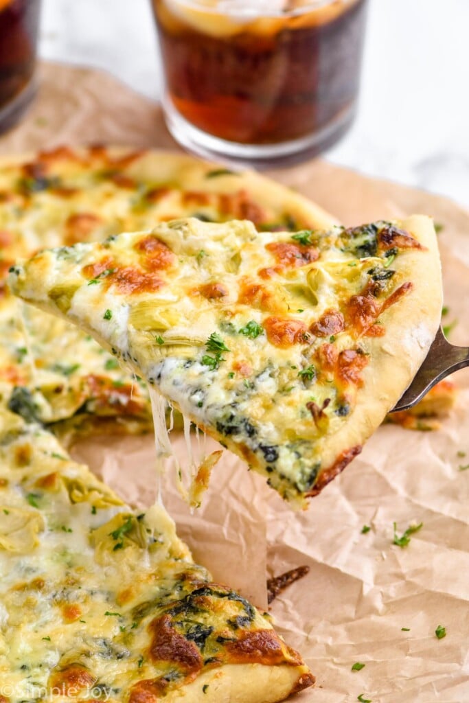 a piece of spinach artichoke pizza being dished up