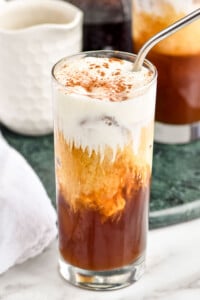 Starbucks Irish cream cold brew copy cat in a tall glass with foam, cocoa powder and a metal straw