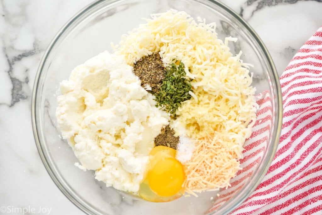 overhead of stuffing for stuffed shells in a bowl broken up by ingredient