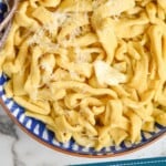 pinterest graphic of overhead of a bowl of homemade egg noodles, cooked, with butter, seasoning and shredded parmesan cheese on it that says "super easy homemade egg noodles simplejoy.com"