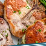 pinterest graphic of close up of stuffed pork chops on a platter with asparagus