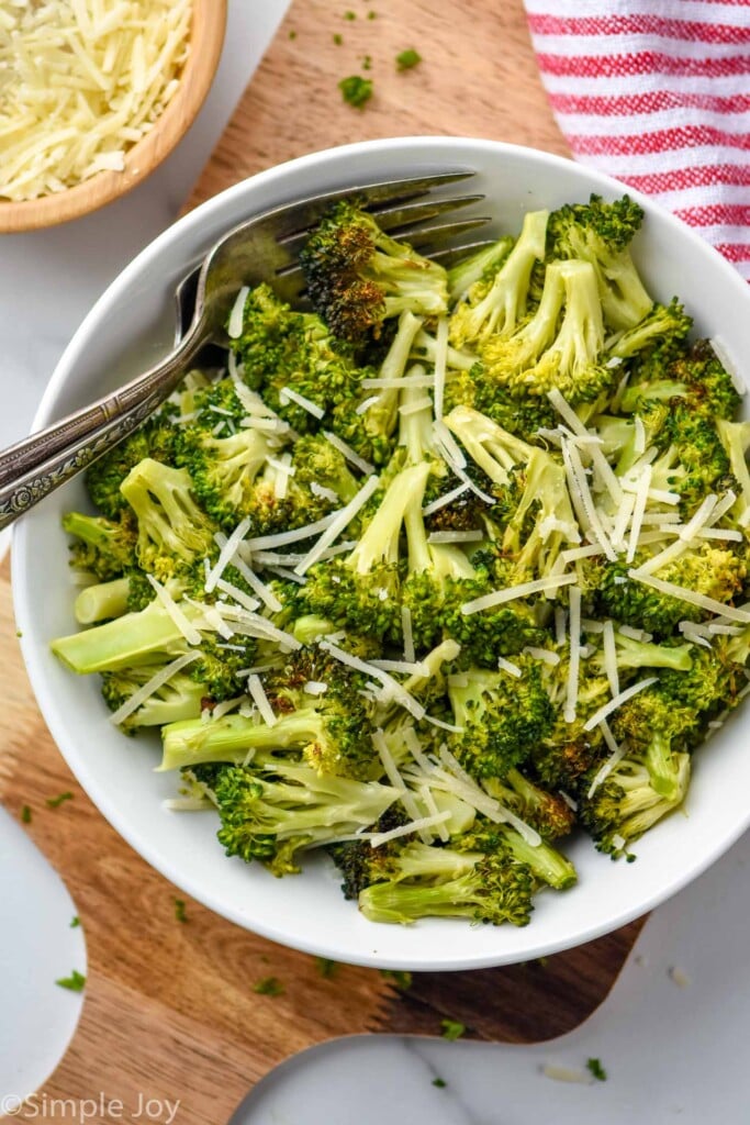 overhead of a white bowl full of air fryer broccoli with shredded parmesan cheese on top