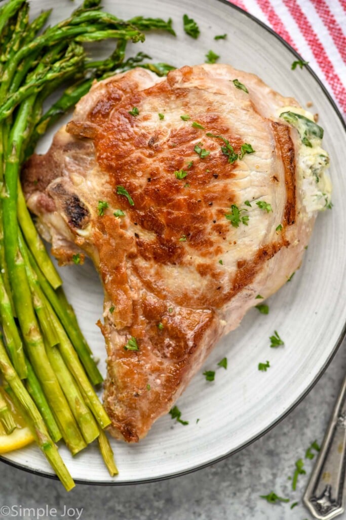 overhead of a baked stuffed pork chop on a plate with asparagus