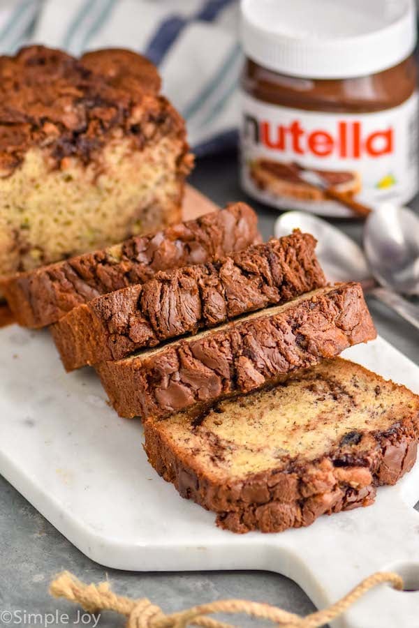 nutella banana bread recipe on a cutting board cut up with a jar of Nutella in the background