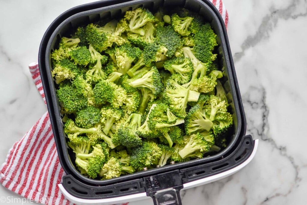 overhead of raw broccoli in the basket of an air fryer