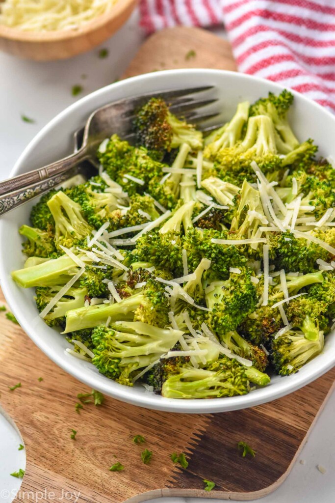 a bowl full of broccoli made in the air fryer topped with shredded parmesan