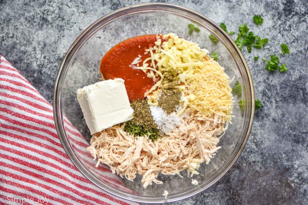 overhead of a bowl full of cream cheese, spaghetti sauce, cheese, chicken and seasonings for chicken stuffed peppers