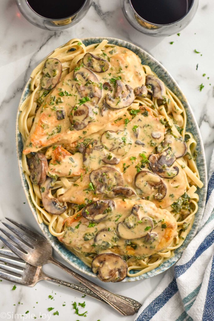 overhead of creamy mushroom chicken on a platter on a bed of linguine