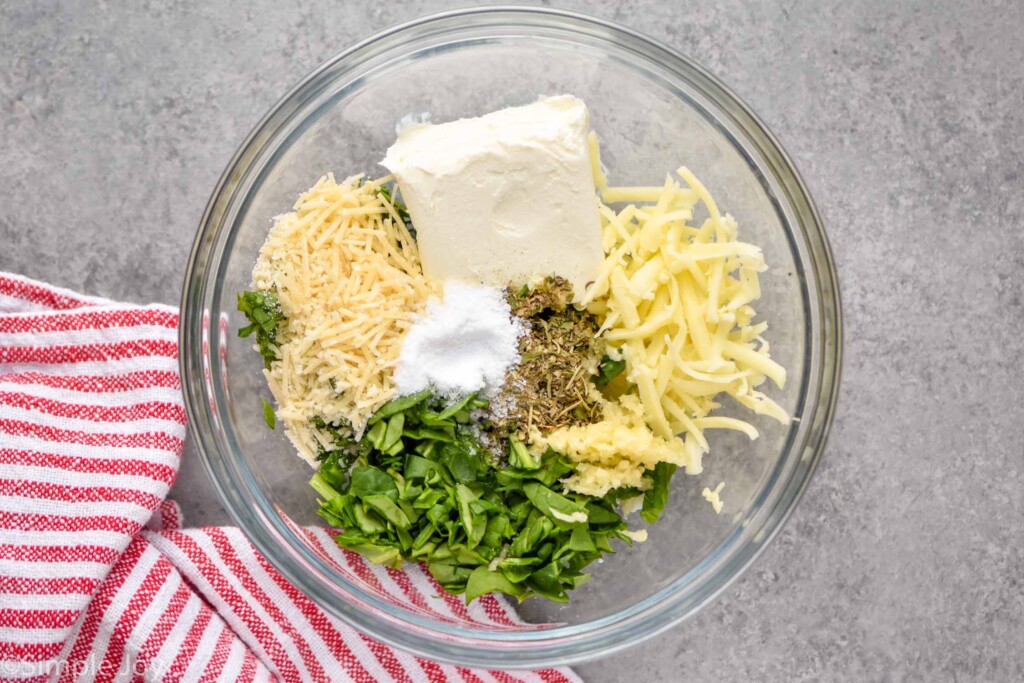 overhead photo of a bowl with cheese, cream cheese, spinach and spices for stuffed pork chops