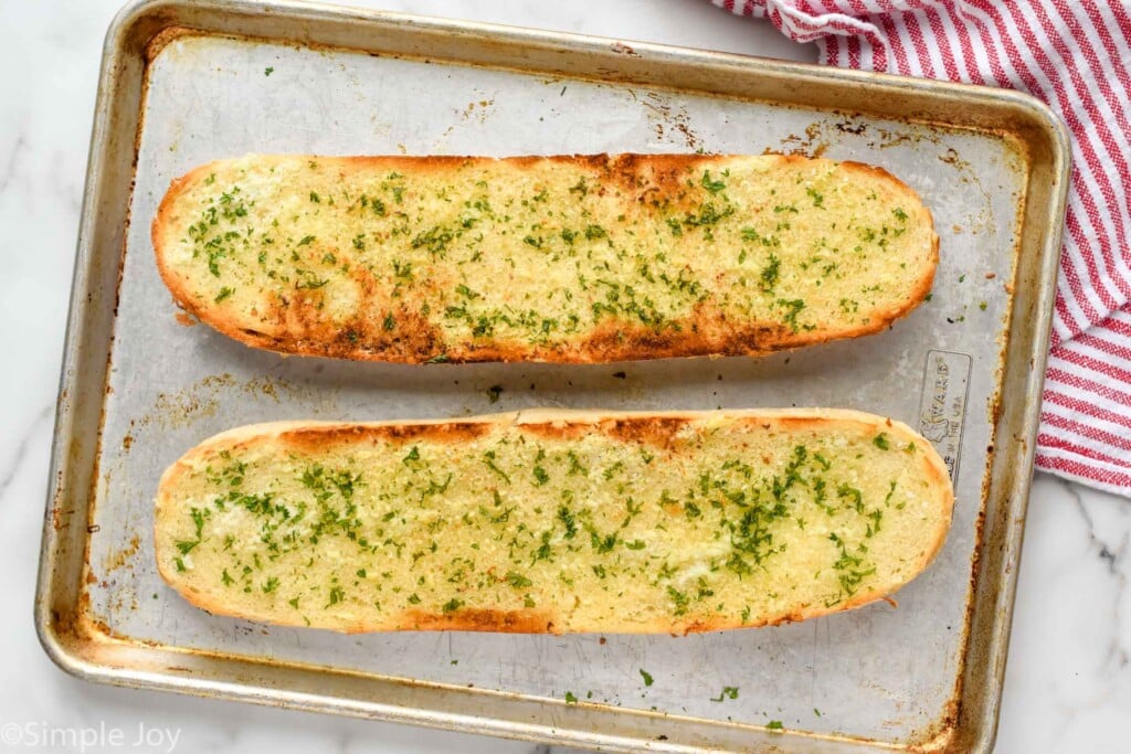 overhead of a rimmed baking sheet with garlic bread on it