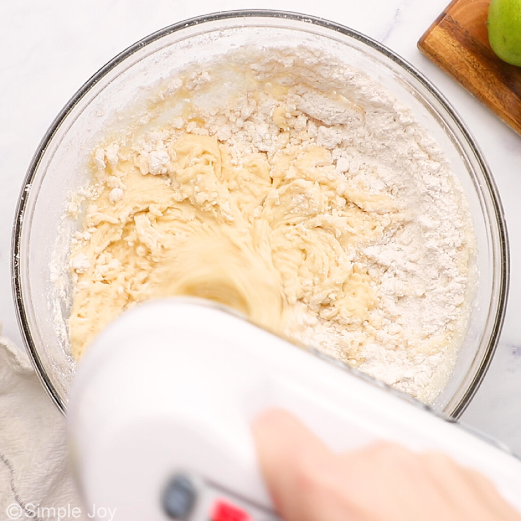 a hand mixer blending flour into wet ingredients