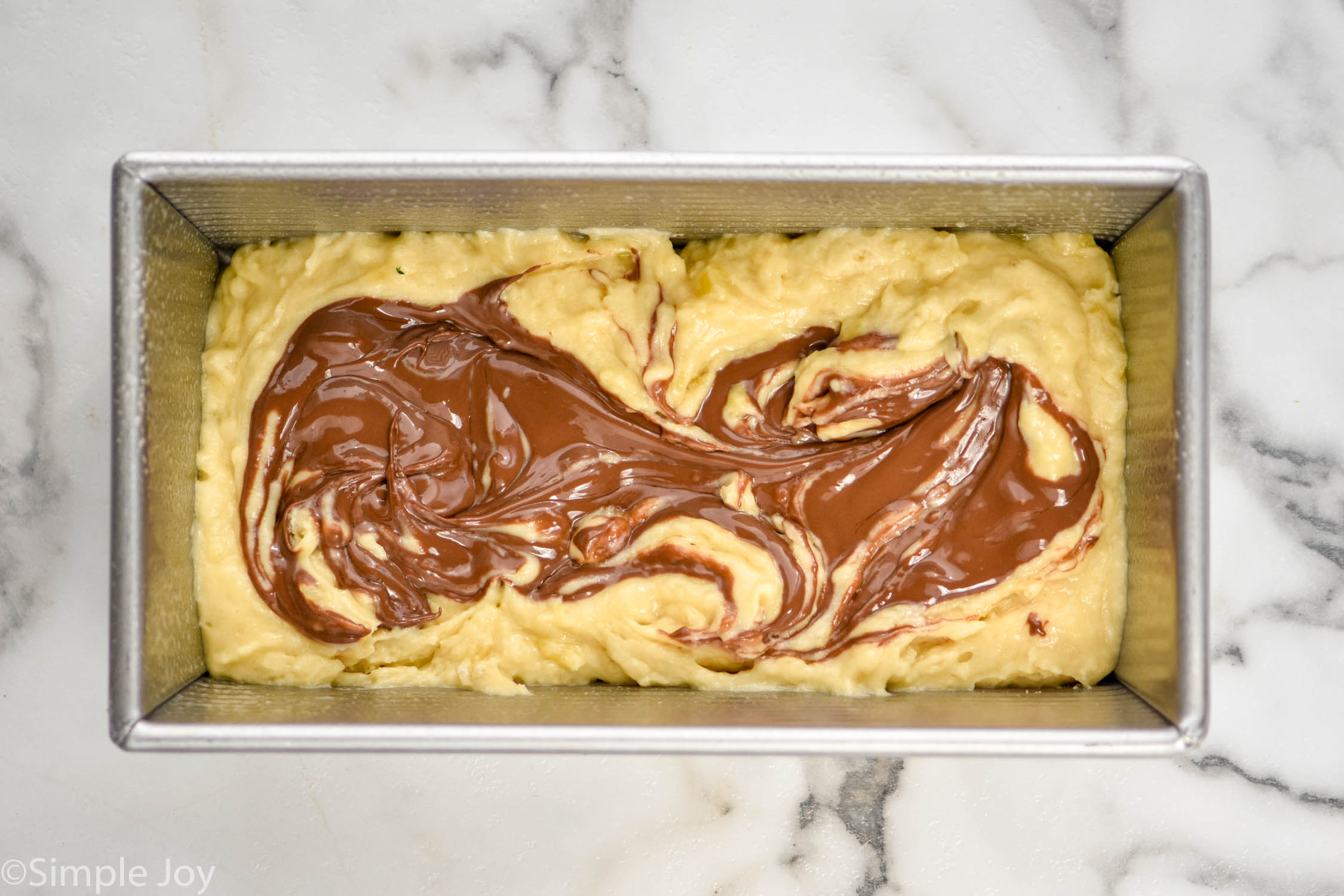 overhead of banana bread batter with Nutella swirled in