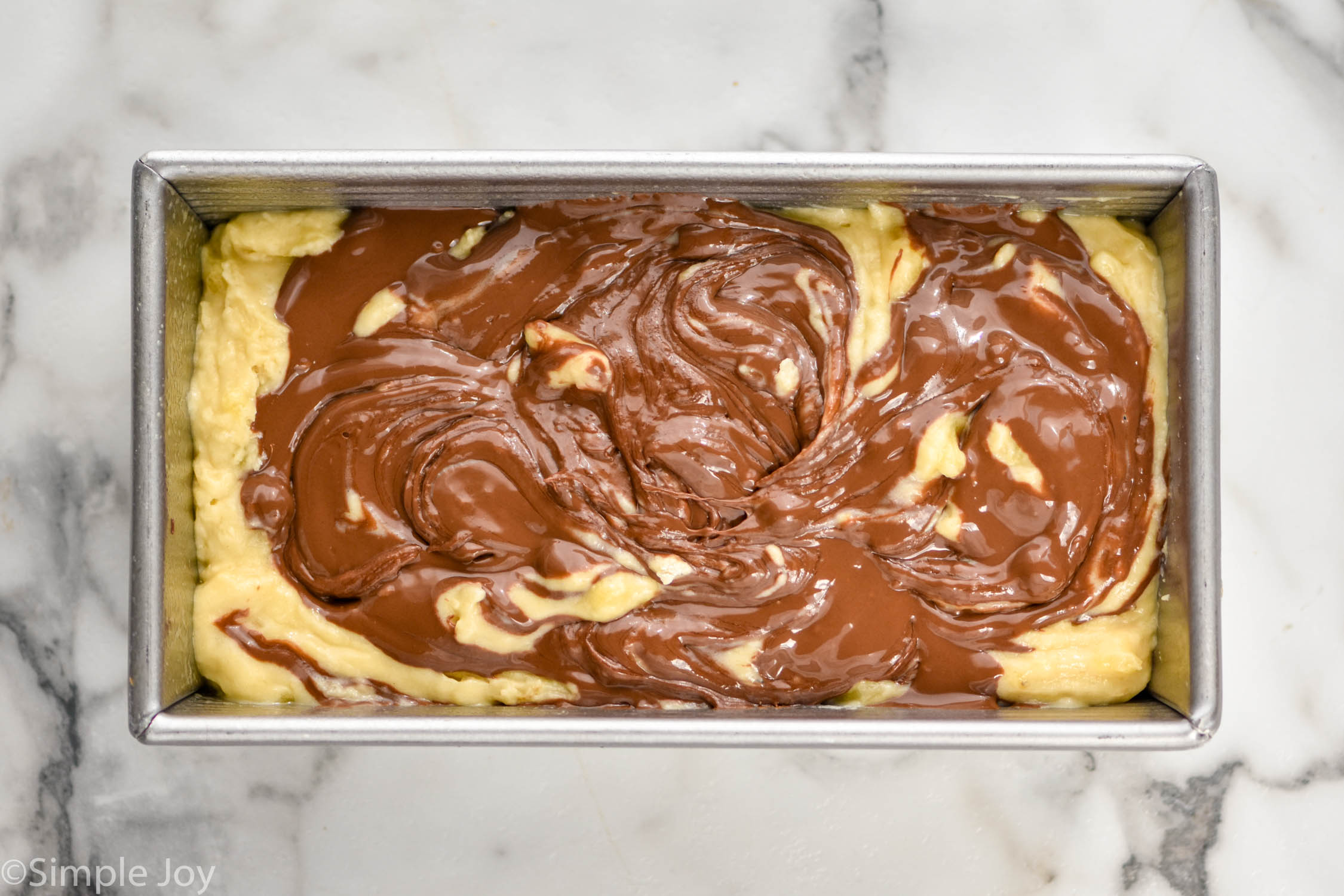 overhead of banana bread batter with Nutella swirled in