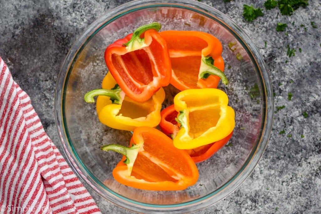 overhead of bell pepper halves that have stems on but insides removed in a large glass bowl