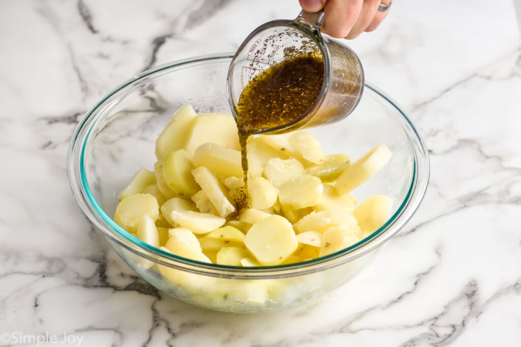 pouring italian seasoned dressing over hot potatoes for a no mayo potato salad