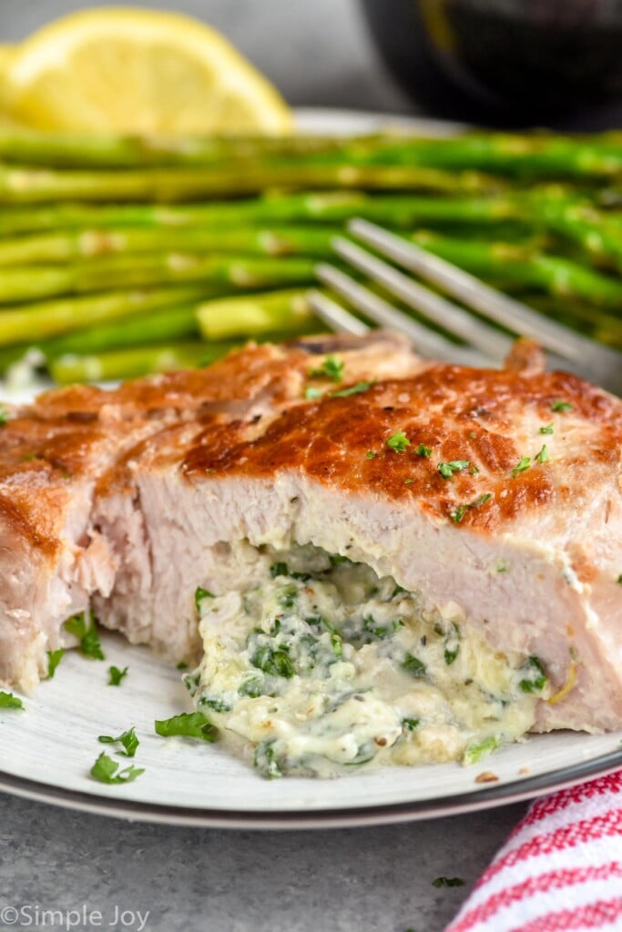 close up of a stuffed pork chop cut in half with cream spinach cheese stuffing coming out