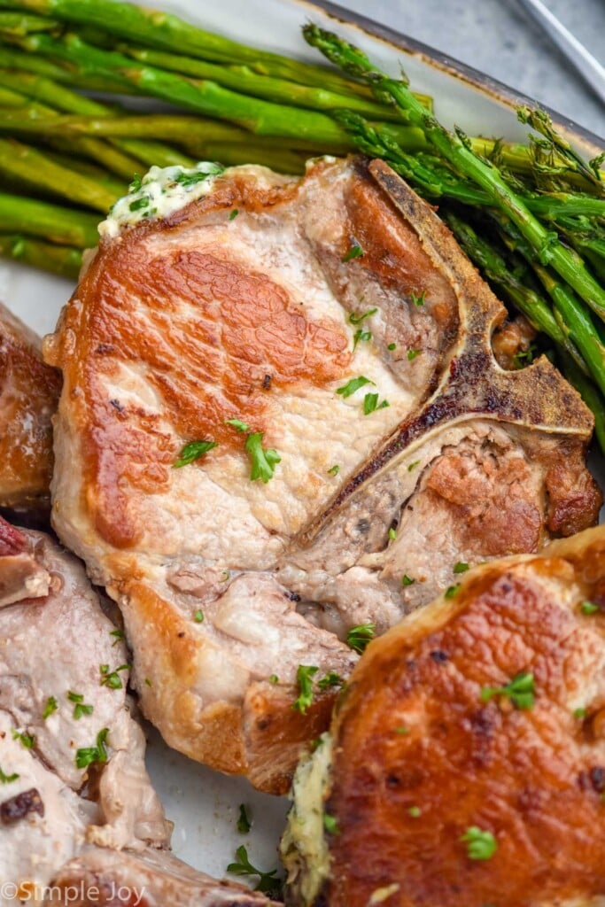 close up of stuffed pork chops on a platter with asparagus