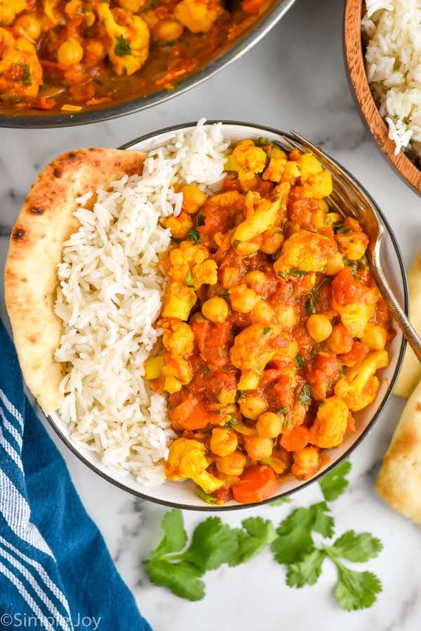 overhead of a bowl of vegetable curry with rice in it and naan