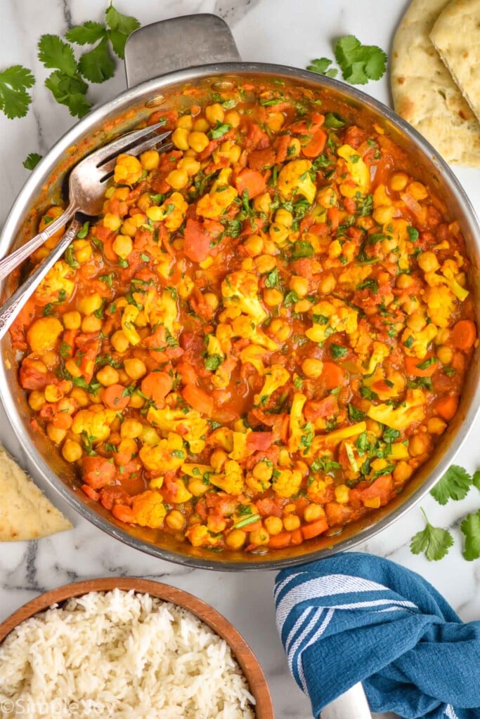 overhead view of a skillet with vegetable curry and two serving forks