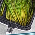 pinterest graphic of overhead photo of air fryer asparagus in the basket of an air fryer, says air fryer asparagus simplejoy.com