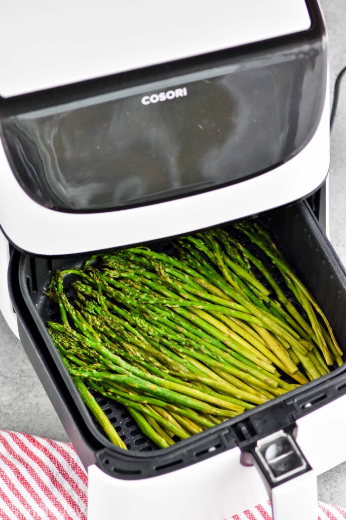 asparagus in the basket of an air fryer, partially in the cosori air fryer