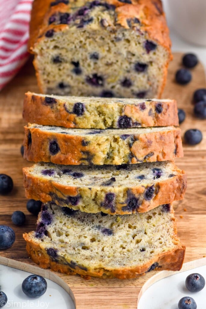 Overhead photo of blueberry banana bread sliced on a wooden cutting board.