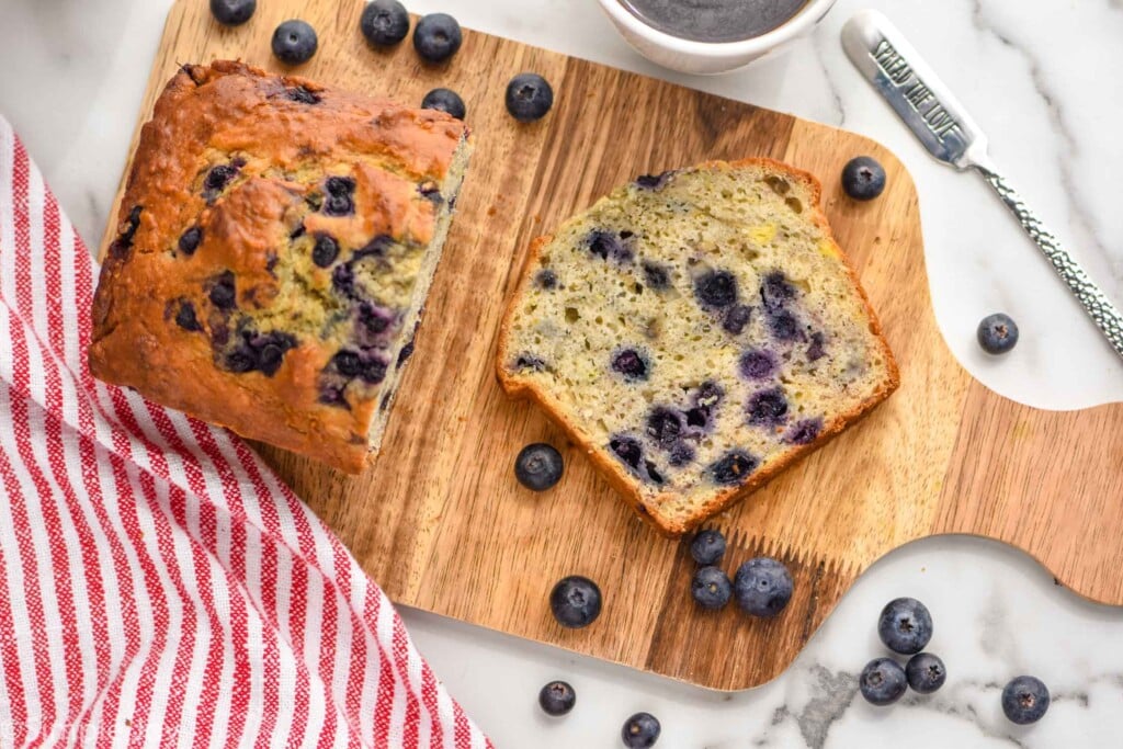 Overhead photo of blueberry banana bread sliced on a wooden cutting board.