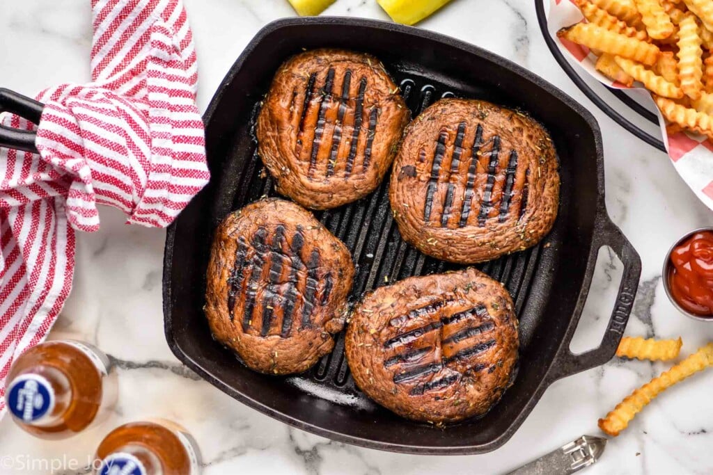 overhead view of four grilled portobello mushroom burgers in a grill pan