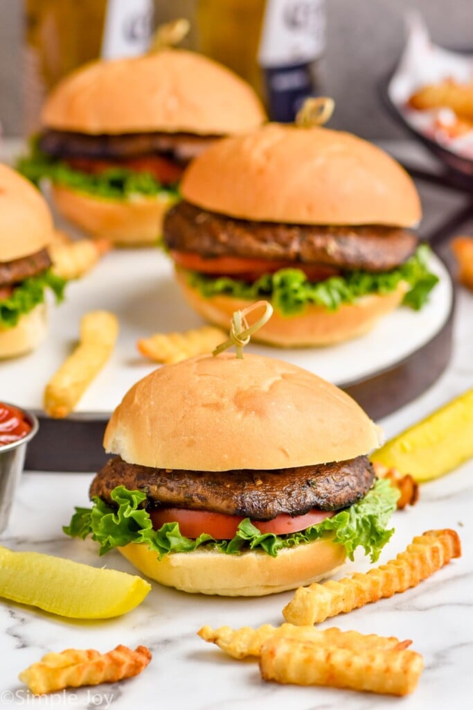 four portobello mushroom burgers on a platter with fries around them