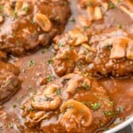 side view of a Salisbury steak recipe in a pan with gravy, garnished with parsley - 15