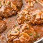 side view of a Salisbury steak recipe in a pan with gravy, garnished with parsley