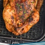 Pinterest graphic of air fryer whole chicken recipe. Overhead photo of air fryer whole chicken in air fryer basket. Text says, "air fryer chicken simplejoy.com"