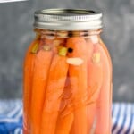 Pinterest graphic of pickled carrots recipe. Sealed Mason jar of pickled carrots sitting on counter top. Text says, "Super Easy Pickled Carrots simplejoy.com"